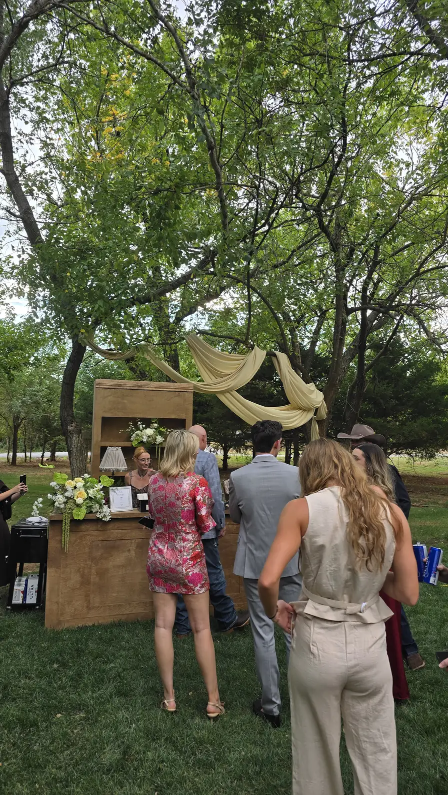 Guests gather at the bar beneath the draped trees