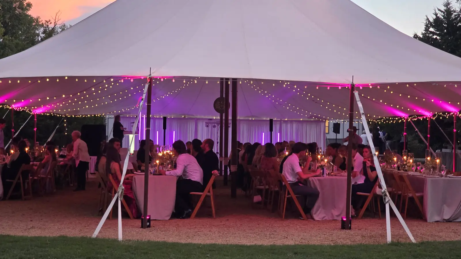 Guests at dinner inside the tent under pink light