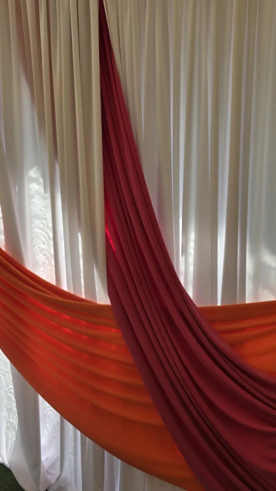 Detail of layered red and orange accent swags over sheer white panels