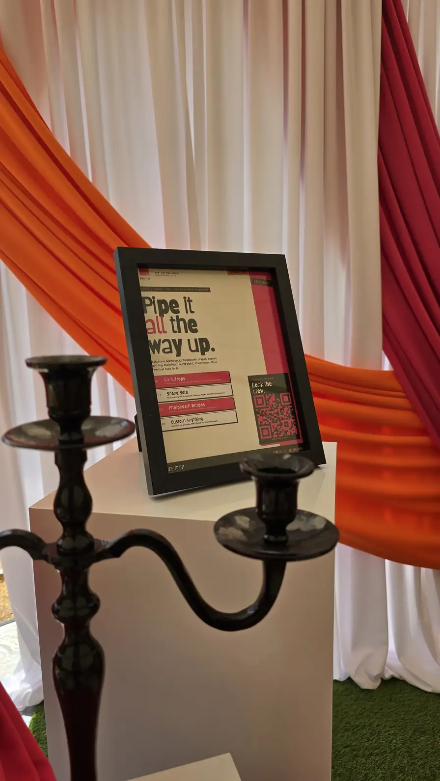 Our sign on a white pillar beside a black candelabra, in front of the accent swags