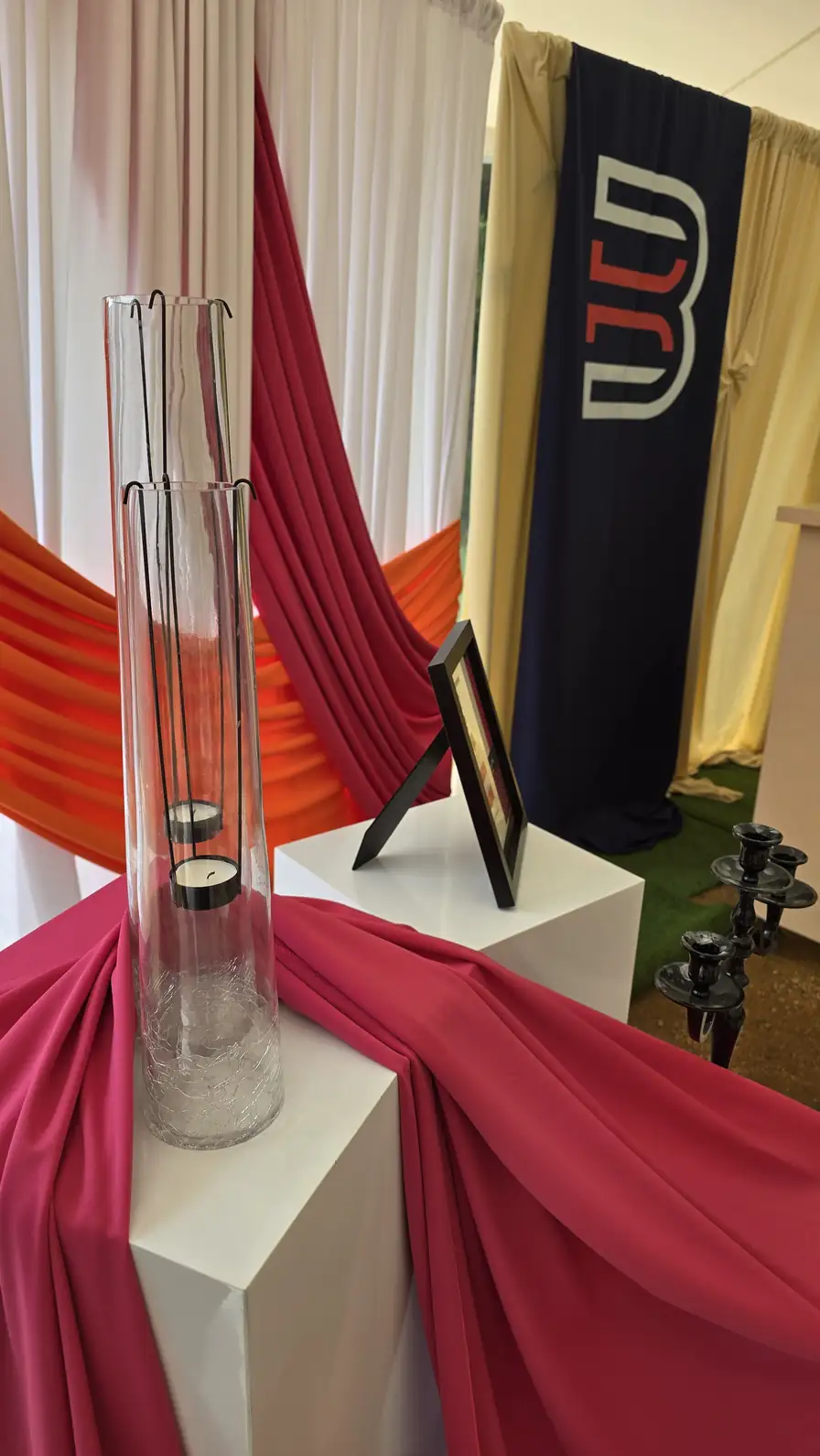 Hot pink fabric pooled over a white pillar in front of the sheer white walls